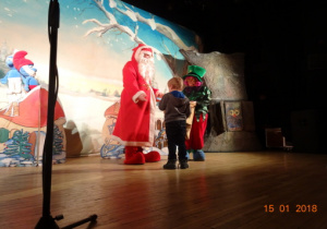 Scenografia - chatka krasnoludków,smerf, na scenie aktor przebrany za Mikołaja, aktorka przebrana za elfa oraz chłopiec.